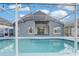 A screened-in pool reflecting the house and sky, offering a serene backyard view at 2570 Chatham Cir, Kissimmee, FL 34746