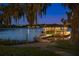 Well-lit boat dock at twilight with a boat in the water and green lawn at 3120 Downs Cove Rd, Windermere, FL 34786