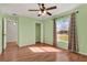 Bright bedroom featuring light green walls, hardwood floors, closet, ceiling fan, and natural light from the window at 3200 Utah Dr, Deltona, FL 32738