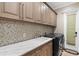 Well-equipped laundry room with granite counters, mosaic tile backsplash and cabinetry for storage at 5524 Sail Ct, Orlando, FL 32819