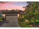 Charming single-story home with a brick driveway, two-car garage, and beautifully landscaped front yard at sunset at 556 Grande Dr, Davenport, FL 33837