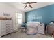 Charming Bedroom with blue accent wall, a white crib, and playful decorations at 650 Peyton Brooke Way, Winter Haven, FL 33881