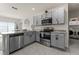 Well-lit kitchen features stainless steel appliances, grey cabinetry and a breakfast bar adjacent to laundry area at 650 Peyton Brooke Way, Winter Haven, FL 33881