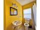 Bright yellow bathroom featuring a pedestal sink and toilet at 7002 Rose Ave, Orlando, FL 32810