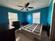 Bedroom with bright blue walls, a ceiling fan and two windows at 7002 Rose Ave, Orlando, FL 32810