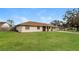 Lawn view of a single story home with a brown roof, a two car garage, and mature trees at 7215 Scenic Pl, Lakeland, FL 33810