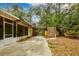 Exterior driveway of house with mature trees, storage shed and access to a screened in porch at 7252 June Bug Ln, Orlando, FL 32818