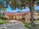 Charming home with a clay tile roof, lush landscaping, and a concrete driveway leading to an attached garage at 8012 S Madeira Ct, Orlando, FL 32836