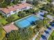 Aerial view of a tennis court surrounded by lush greenery and multi-story residential buildings at 8323 Bella Vida Cir, Davenport, FL 33896