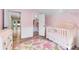 Bright and cozy baby bedroom with a pink rug and a crib near the closet, creating a cheerful space at 8712 Irmastone Way, Orlando, FL 32817