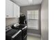 Laundry room featuring gray walls, black washer and dryer, white cabinets and a window at 909 E Central Blvd, Orlando, FL 32801