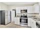 Modern kitchen featuring stainless steel appliances, updated white cabinets, and granite countertops at 913 Ferndell Rd, Orlando, FL 32808