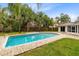 Backyard pool with brick deck, landscaping, palm trees, and covered porch at 922 Puma Trl, Winter Springs, FL 32708