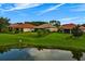 Picturesque view of several single-story homes with manicured lawns and a serene pond reflecting the sky at 9235 San Jose Blvd, Howey In The Hills, FL 34737