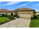 Exterior view of a tan home featuring a tile roof, two-car garage, and beautifully paved driveway at 9235 San Jose Blvd, Howey In The Hills, FL 34737