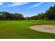 Picturesque golf course view featuring lush green fairways, mature trees, and a sand bunker at 9235 San Jose Blvd, Howey In The Hills, FL 34737