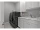 Well-lit laundry room featuring modern washer and dryer, sink, and ample white cabinet space at 9235 San Jose Blvd, Howey In The Hills, FL 34737