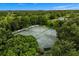 Aerial view of the tennis courts surrounded by dense, mature trees at 9235 San Jose Blvd, Howey In The Hills, FL 34737