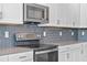 Close up of kitchen with stainless steel appliances, dark subway tile backsplash, and light gray countertops at 9834 Introduction Way, Orlando, FL 32832