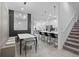 Open floor plan combines dining area with modern table set, island with bar stools, and elegant staircase at 10364 Ebb Tide Ln, Orlando, FL 32821