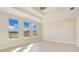 Bright bedroom with tray ceiling and large windows overlooking a serene pond view at 11464 Beau Repost Dr, Orlando, FL 32832