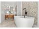 Bright bathroom featuring a soaking tub, penny tile accent wall, wood vanity with double sinks and a large mirror at 1404 Kelso Blvd, Windermere, FL 34786