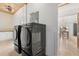 Modern laundry room with wooden ceiling, subway tile wall, and black front load washer and dryer at 1404 Kelso Blvd, Windermere, FL 34786