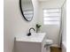 Stylish bathroom featuring a sleek vanity with a matte black faucet, an oval mirror, and walk-in shower at 1607 31St Nw St, Winter Haven, FL 33881