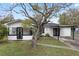 Charming single-story home with a manicured lawn, modern black trim, and a convenient carport for covered parking at 1607 31St Nw St, Winter Haven, FL 33881