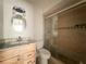 This bathroom features a round mirror, wooden cabinets and a tiled shower with glass doors at 163 Springwood Cir # D, Longwood, FL 32750
