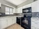 Kitchen features white cabinets, black appliances, mosaic backsplash and granite countertops at 163 Springwood Cir # D, Longwood, FL 32750