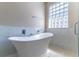 Modern bathroom featuring a freestanding tub, tiled walls, glass block window, and modern fixtures at 1714 Golfview Dr, Kissimmee, FL 34746