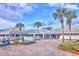 Beautiful clubhouse featuring manicured landscaping, palm trees and golf carts under a cloudy, blue sky at 2007 Cornell Pl # 4, Port Orange, FL 32128
