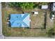 Overhead view of a home with a distinctive blue roof, fenced yard, and surrounding greenery at 3512 Central Ave, Coleman, FL 33521