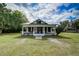 Charming home featuring a covered front porch, white siding, black window trim, and a beautifully landscaped lawn at 3512 Central Ave, Coleman, FL 33521