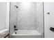 Bathroom features a white bathtub with marble tiled walls and modern, matte black fixtures at 411 St Johns Ln, Kissimmee, FL 34759