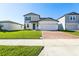 Charming two-story home with a well-manicured lawn and a brick paved driveway on a sunny day at 4514 Windy Oak Way, St Cloud, FL 34772