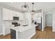 Well-lit kitchen with stainless steel appliances, a kitchen island and white cabinets with stylish pendant lighting at 5093 Railroad Vine Aly, Winter Garden, FL 34787