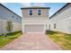 Neat two-story home featuring a brick driveway, garage, well-kept lawn, and complementary neutral-toned siding at 5099 Railroad Vine Aly, Winter Garden, FL 34787