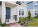 Inviting front porch view with a blue entry door, black railings and brick-laid walkway at 5099 Railroad Vine Aly, Winter Garden, FL 34787