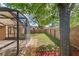 A partially-fenced backyard with an enclosed patio and a large shady tree at 5580 Berwood Dr, Orlando, FL 32810