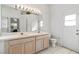Bathroom featuring a double sink vanity, large mirror with decorative lighting, and a toilet at 647 Ella Mae Dr, Davenport, FL 33897