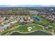 Panoramic aerial shot of homes nestled within a golf course community, surrounded by trees and a tranquil lake at 7233 Se 171St Pond Ln, The Villages, FL 32162