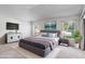 This bedroom includes a gray platform bed, wall-mounted TV, and ample natural light from large windows at 7233 Se 171St Pond Ln, The Villages, FL 32162