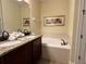 Bathroom featuring a granite countertop double vanity and a built-in tub at 7668 Wilmington Loop, Kissimmee, FL 34747