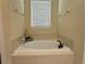 Cozy bathroom featuring a built-in tiled bathtub with chrome hardware and a window at 7668 Wilmington Loop, Kissimmee, FL 34747