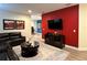 Spacious living room with a sectional sofa, media center, and a bold red accent wall at 7668 Wilmington Loop, Kissimmee, FL 34747