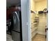 Well-organized pantry with shelves, providing ample storage space next to stainless steel fridge at 7668 Wilmington Loop, Kissimmee, FL 34747