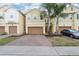 Inviting townhomes feature two-car garages, brick paver driveways, lush landscaping, and mature palm trees at 9819 Red Eagle Dr, Orlando, FL 32825