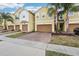 Inviting townhomes feature two-car garages, brick paver driveways, lush landscaping, and mature palm trees at 9819 Red Eagle Dr, Orlando, FL 32825